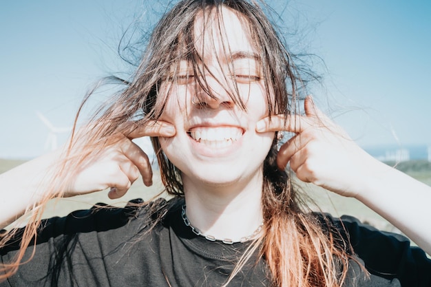 Young happy fun carefree girl smiling with big teeth to camera\
while pointing her dimples to camera bright and great future\
concept sustainable world new generations gen z world modern\
look