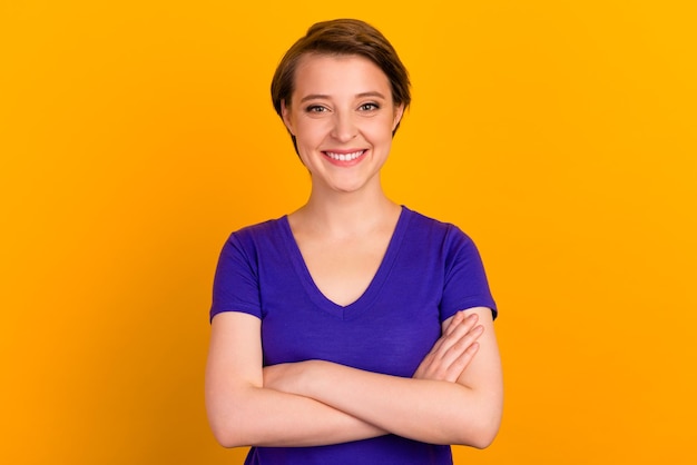 Young happy fun confident woman hands crossed isolated on yellow color background studio portrait