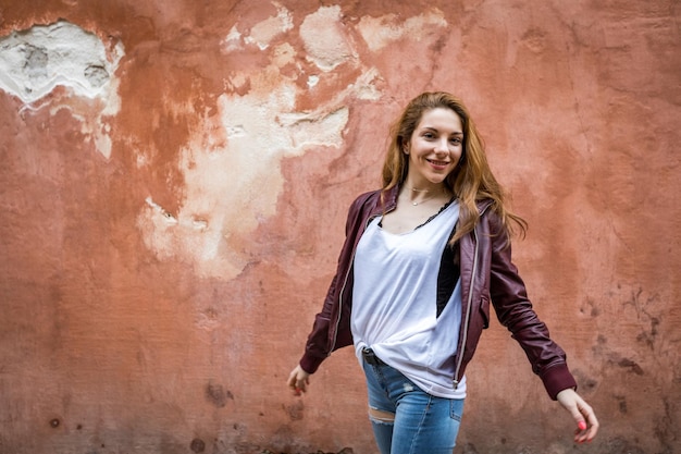 Young and happy girl in casual clothes on a red wall background with copy space