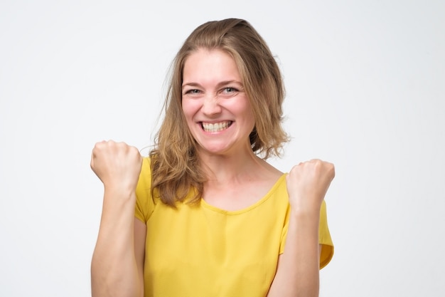 Young happy girl gestures fists, isolated