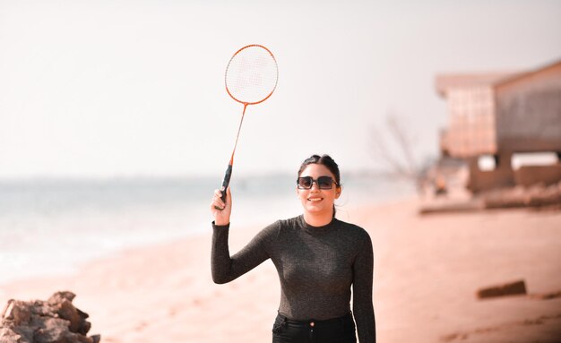 ビーチでテニスをしている若い幸せな女の子インドのパキスタンモデル