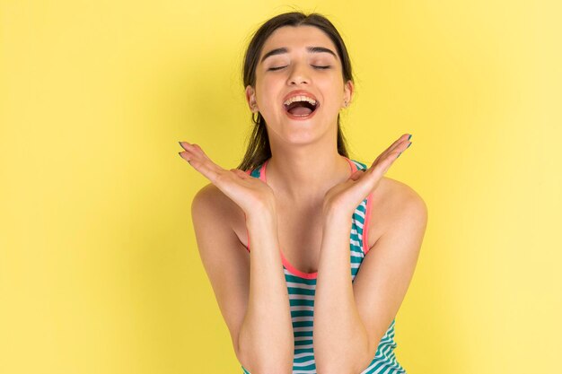 Young happy girl standing on yellow background and laughing High quality photo