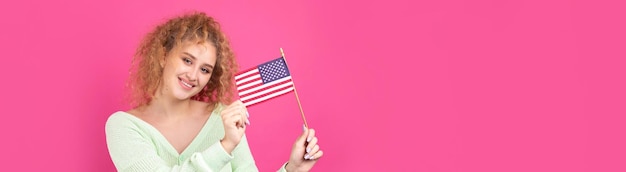 A young happy girl with a smile on her face holds an American flag in her hands Symbol of patriotism and freedom