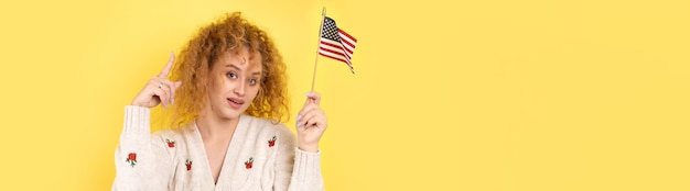 A young happy girl with a smile on her face holds an American flag in her hands Symbol of patriotism and freedom