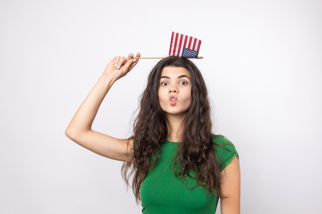 A young happy girl with a smile on her face holds an American flag in her hands