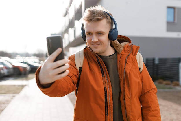 Photo young happy guy is making selfie on a phone man walking in spring city outdoors urban lifestyle concept traveler