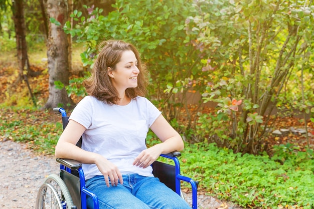患者サービスを待っている病院公園の道路上の車椅子の若い幸せなハンディキャップの女性