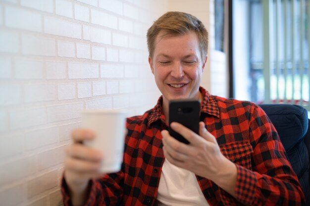 Young Happy Hipster Man Drinking Coffee While Using Phone