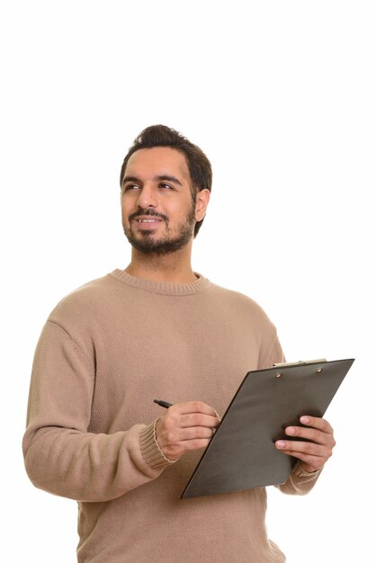 Young happy Indian man writing report on clipboard while thinkin