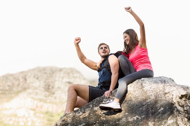 Young happy joggers sitting on rock cheering 