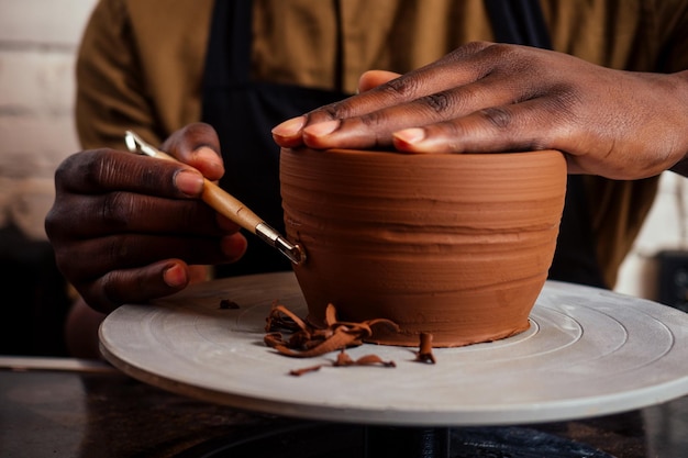 Young and happy latino american businessman creating molds a\
handmade clay hands pot vase in workshop sculptor creative studio\
workspace earthenware eco product