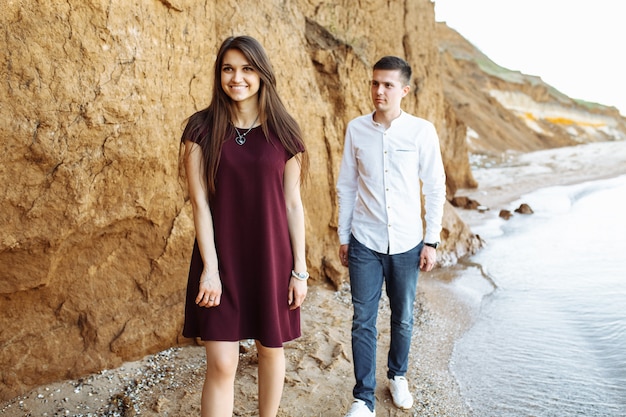 Young, happy, loving couple, near the sand wall, on the sea, posing