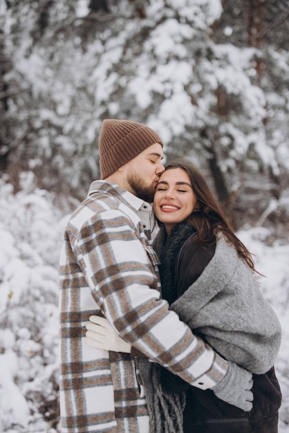 A young happy and loving couple walking in a winter snowy forest in the mountains