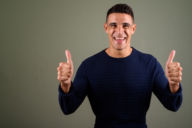 Young happy man giving thumbs up against colored background