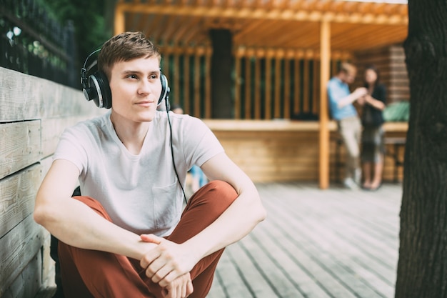 Young happy man in headphones outdoors