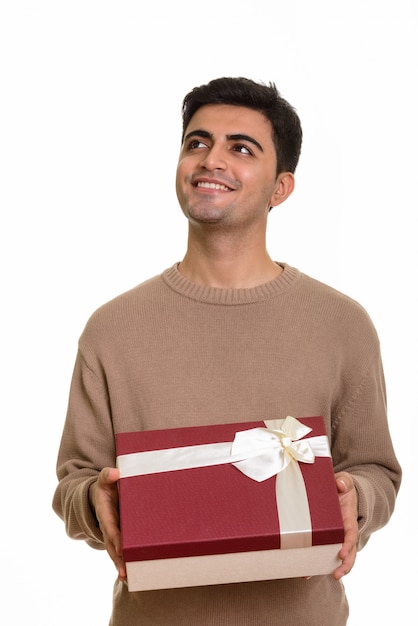 Young happy man holding gift box while thinking