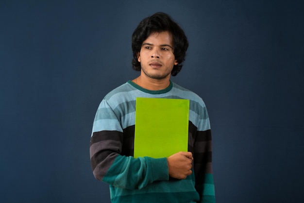 Young happy man holding and posing with the book on background