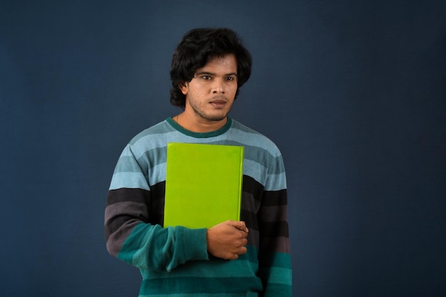 Young happy man holding and posing with the book on background