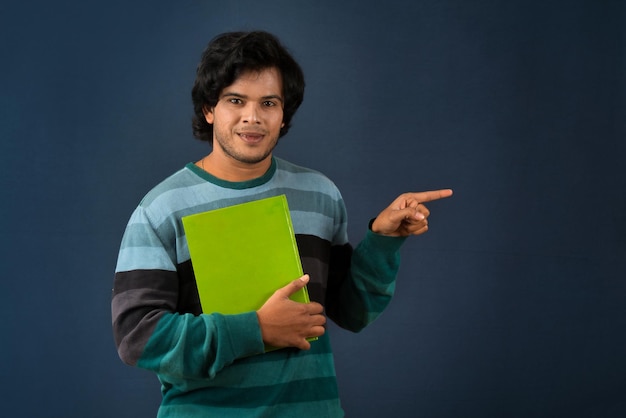 Young happy man holding and posing with the book on background