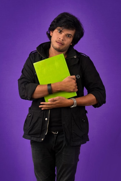 Young happy man holding and posing with the book on background