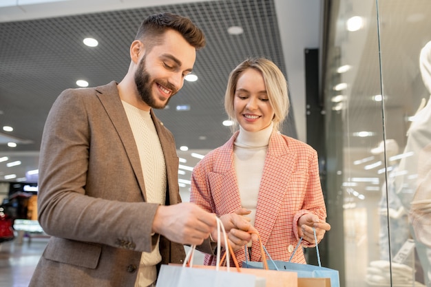 ショッピングバッグを見て、スタイリストとの買い物に満足している若い幸せな男