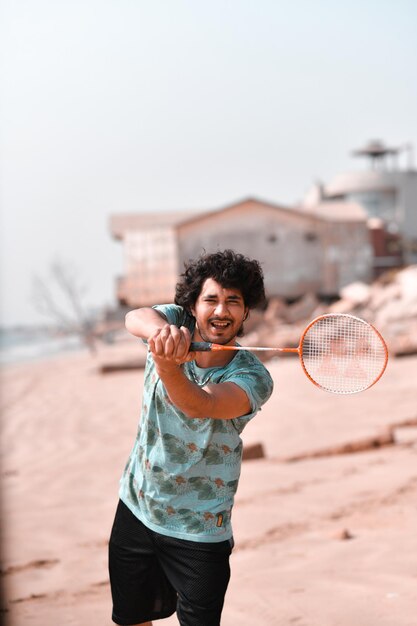 young happy man playing tennis on beach indian pakistani model