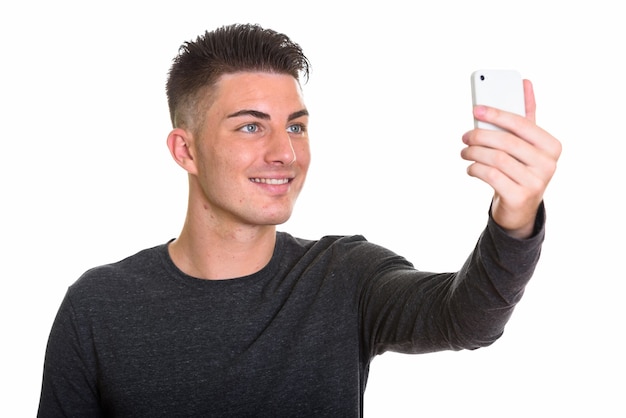 携帯電話でselfieを取って笑っている若い幸せな男