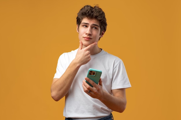 Young happy man using his phone against yellow background