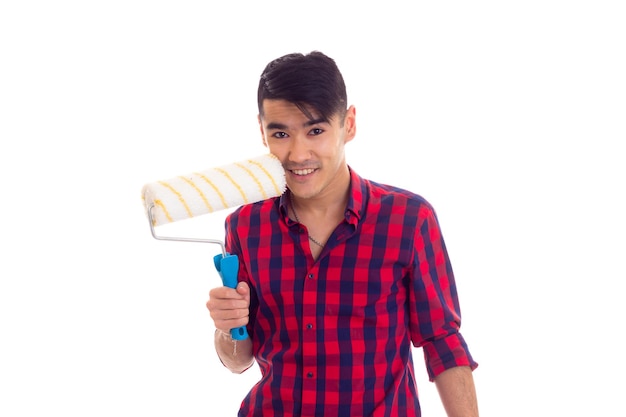 Young happy man with dark hair in red plaid shirt holding white roll on white background in studio