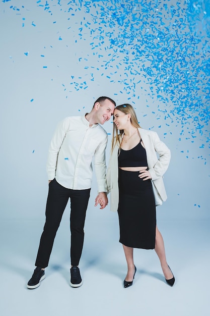 Молодая счастливая супружеская пара обнимается в голубых конфетти Пара узнала пол ребенка Гендерная фотосессия