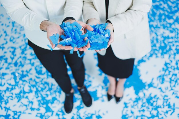 Young happy married couple hugging in blue confetti A couple in love rejoices and has fun Gender photo session