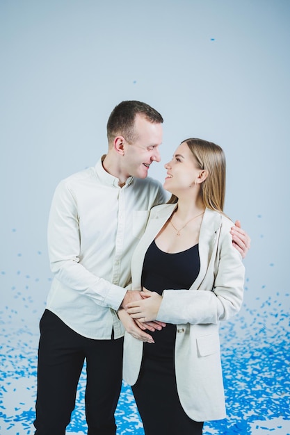 Young happy married couple hugging in blue confetti A couple in love rejoices and has fun Gender photo session