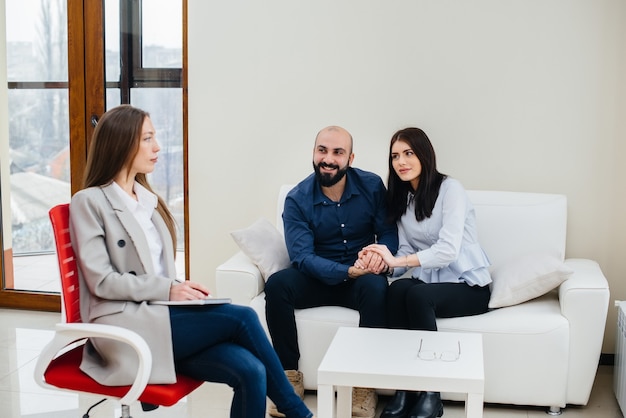 A young happy married couple of men and women talk to a psychologist at a therapy session. Psychology.