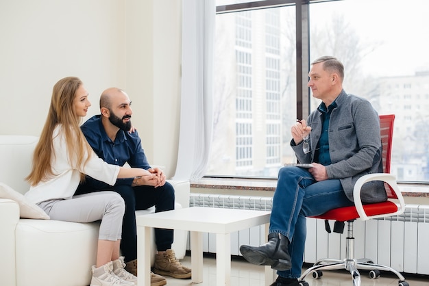 A young happy married couple of men and women talk to a psychologist at a therapy session. Psychology.