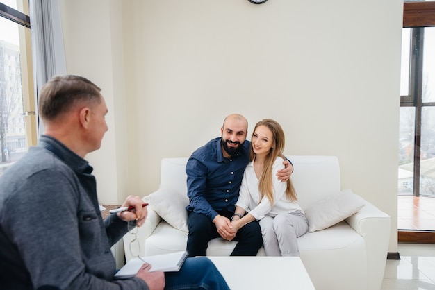 A young happy married couple of men and women talk to a psychologist at a therapy session