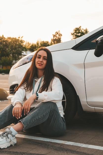 young happy millennial brunette woman sitting next to car young attractive woman in the car