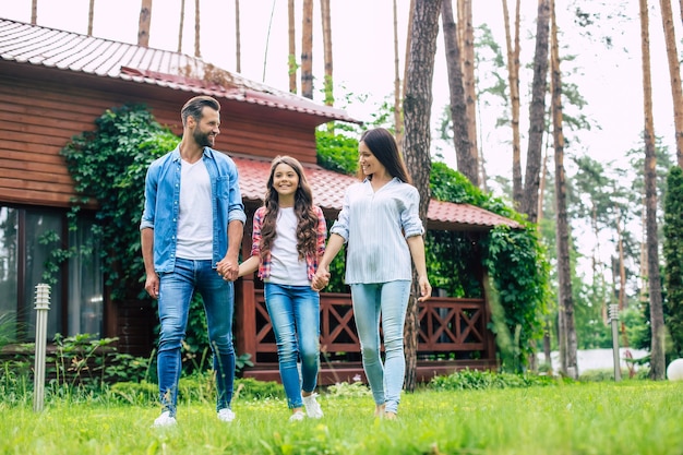 Young happy modern parents with a cute daughter are walking outdoors