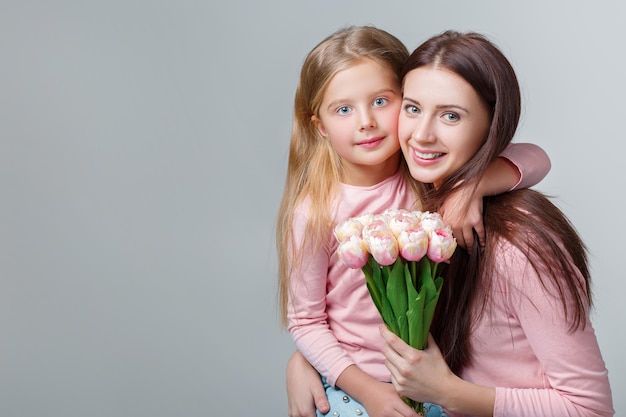 Young happy mother and daughter with bouquet of tulips