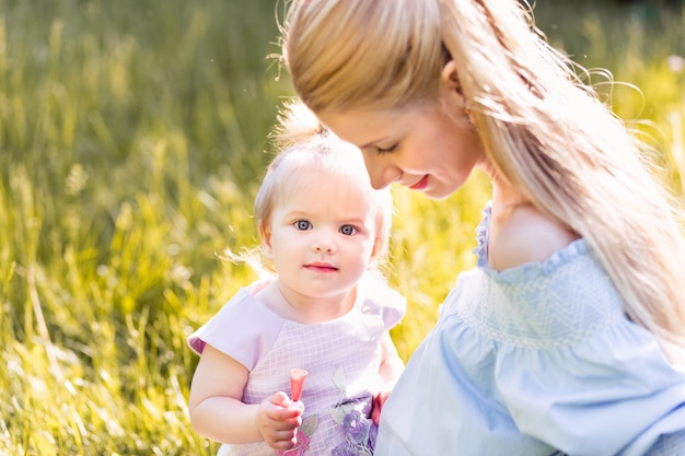 Young happy mother with her baby girl at sunny summer day