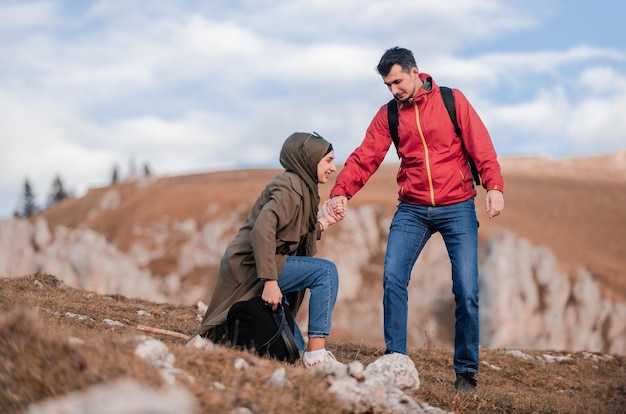 幸せなイスラム教徒の若い夫婦が山をハイキングしながら散歩ルートで休憩している