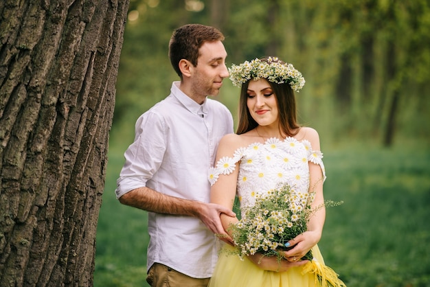 Giovani sposi felici che abbracciano in un parco di primavera, close-up