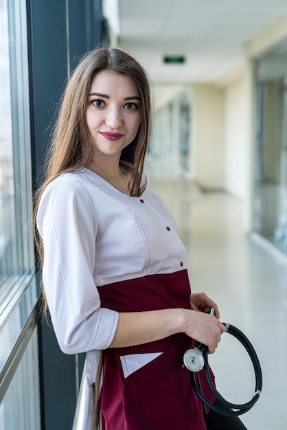 Young happy nurse standing in hospital ward smiling to patients