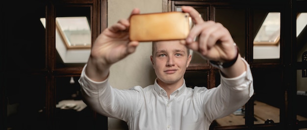Foto il giovane impiegato di concetto felice fa il selfie sul posto di lavoro con lo smartphone