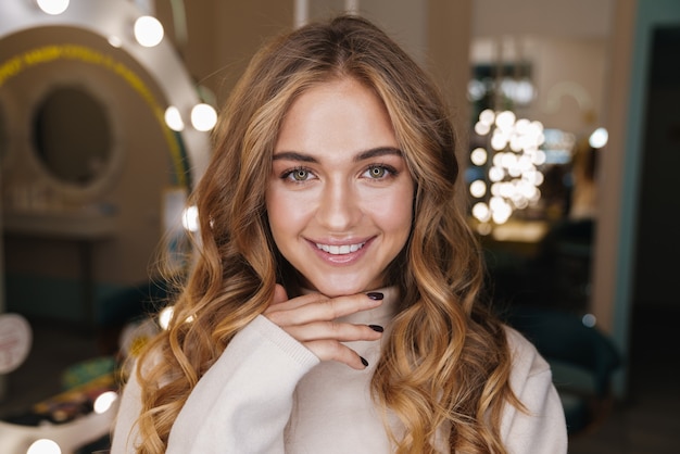 young happy optimistic cute cheery blonde girl indoors in beauty salon looking