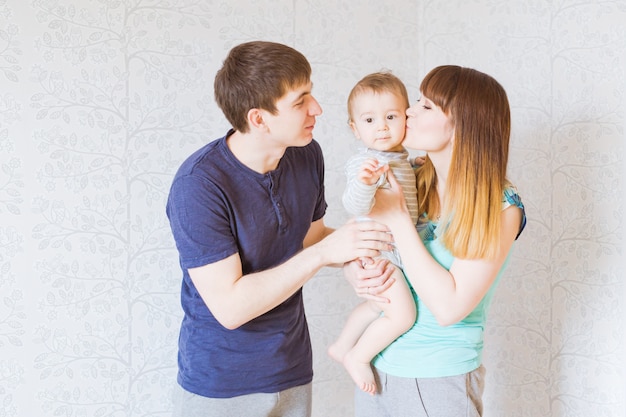 Young happy parents kissing baby boy, mother and father and son