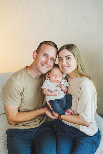 Young happy parents with a newborn baby in their arms at home on the couch Mom and dad with a newborn baby on a white background