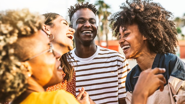 Giovani felici che ridono insieme - gruppo di amici multirazziali che si divertono sulla strada della città - ritratto di studenti di cultura diversa che celebrano fuori - amicizia, comunità, gioventù, concetto universitario.