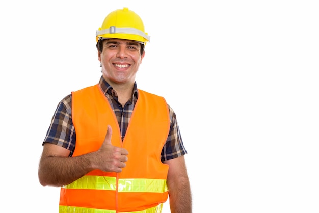 молодой счастливый персидский рабочий-строитель улыбается и дает большой палец вверх