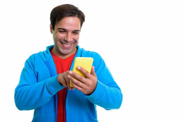 young happy Persian man smiling while using mobile phone