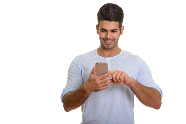 Young happy Persian man smiling while using mobile phone